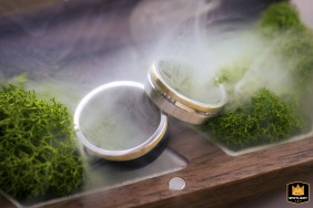 At a hotel in Budapest, two wedding rings rest among vibrant moss, with a prism effect giving the scene a dreamy symbol of unity and love.
